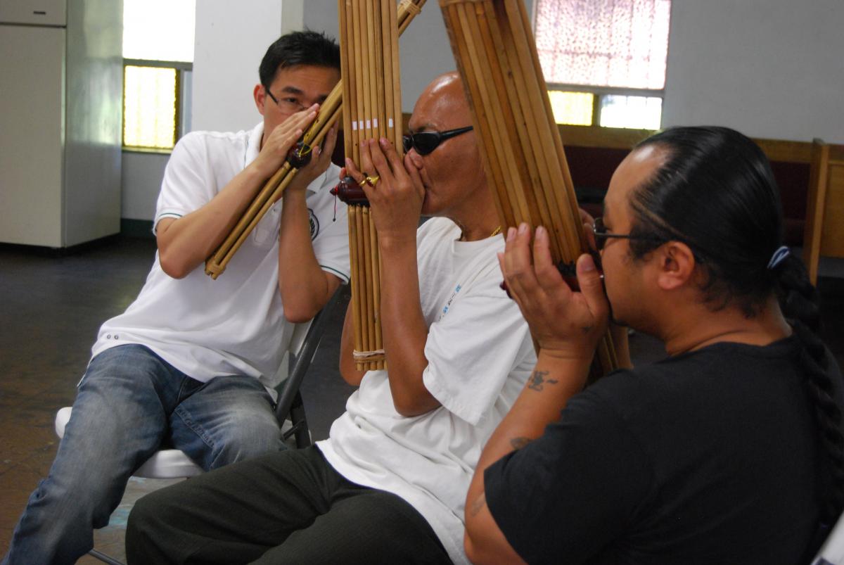 From left: Apprentice Monty Bouasone, master artist Bounseung Synanonh, and Sangkhom Chomthong practice the khene at  Fresno Interdenominational Refugee Ministries.