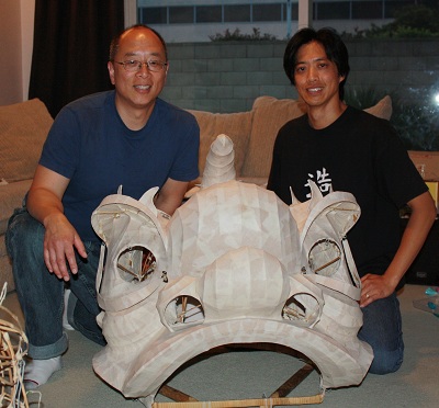 Corey Chan with his apprentice Chris Low and the lion head in the process of restoration.