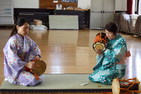 Master artist, Kimisen Katada (Mariko Watabe) plays the kotsuzumi drum accompanied by her apprentice Amy Smith who plays the ōtsuzumi drum, both of which are of the Japanese Hayashi classical percussion tradition.