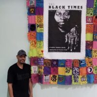 William Rhodes standing next to the Knotted Community quilt. Seniors and Youth helped to create this quilt.