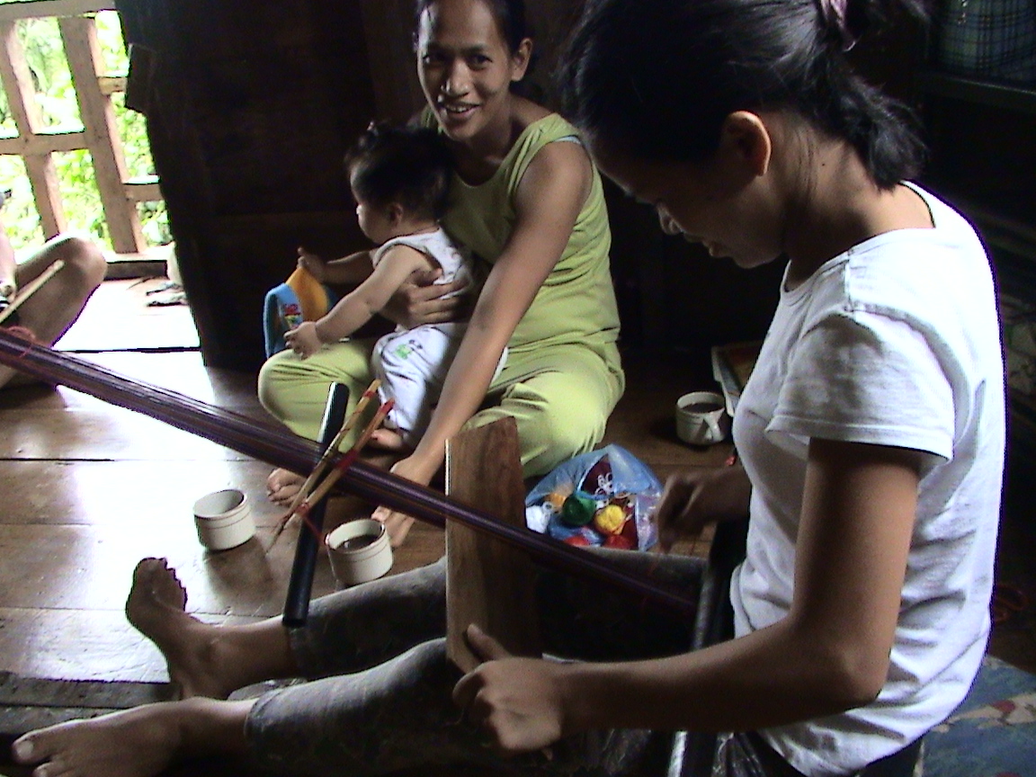 Luguagan Weaver: Mabilong weaver braces her feet while Irene Bimuyag holds her baby.