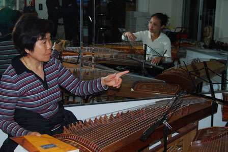 Master Artist Weishan Liu (left) instructs apprentice Regina Ngo in a private lesson at Liu’s mirrored home studio in San Francisco, overflowing with Gu Zheng for use by her many students.